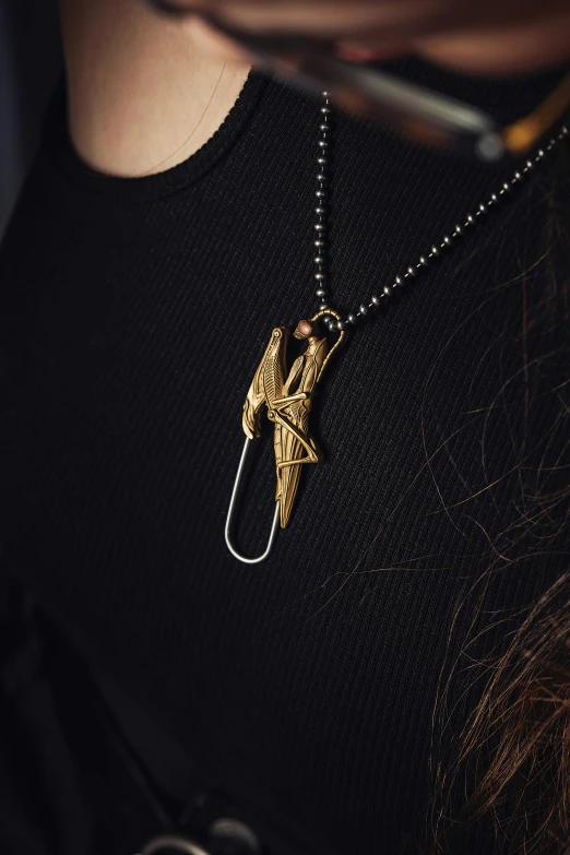 the necklace features a bird like motif that is on a gold tone chain