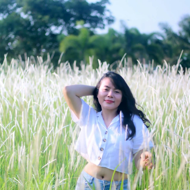 a young asian woman is posing in the middle of a grassy field