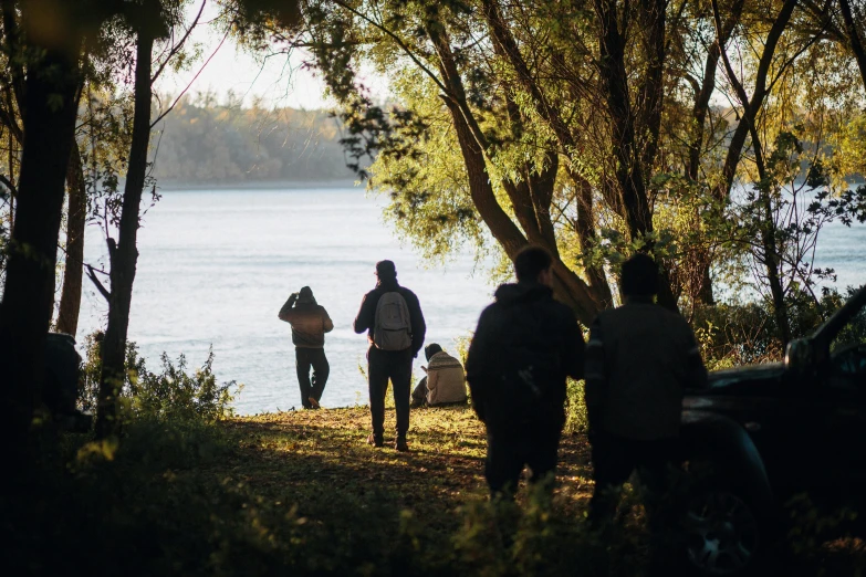 three people walking by a lake carrying coolers