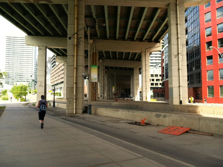 a person walking under a bridge by buildings