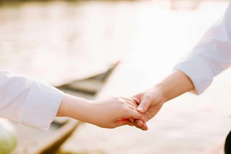 the couple is holding hands by the boat in the lake