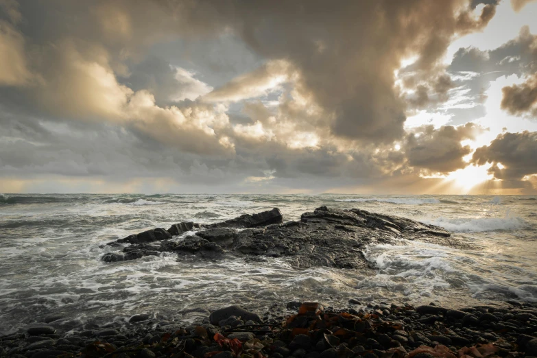 a small rock on a rocky shore as the sun sets