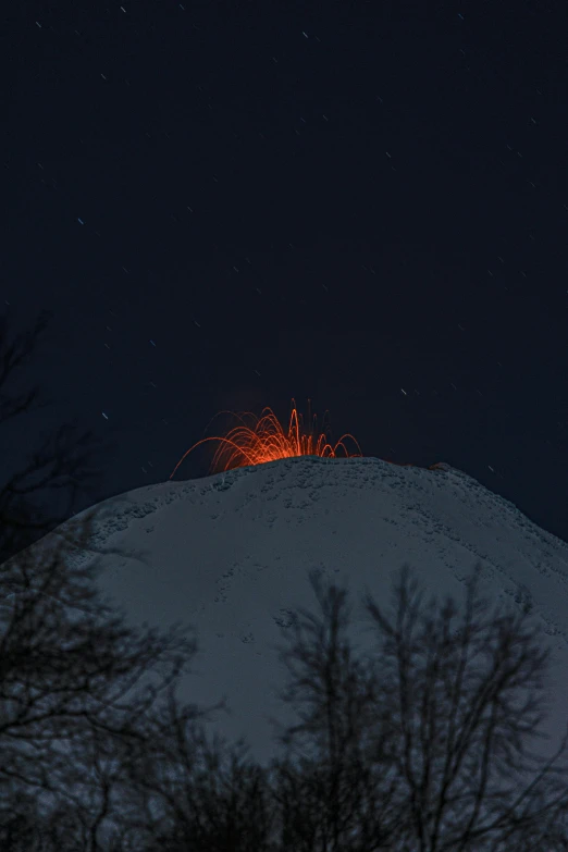 a snow covered hill with small, orange lights