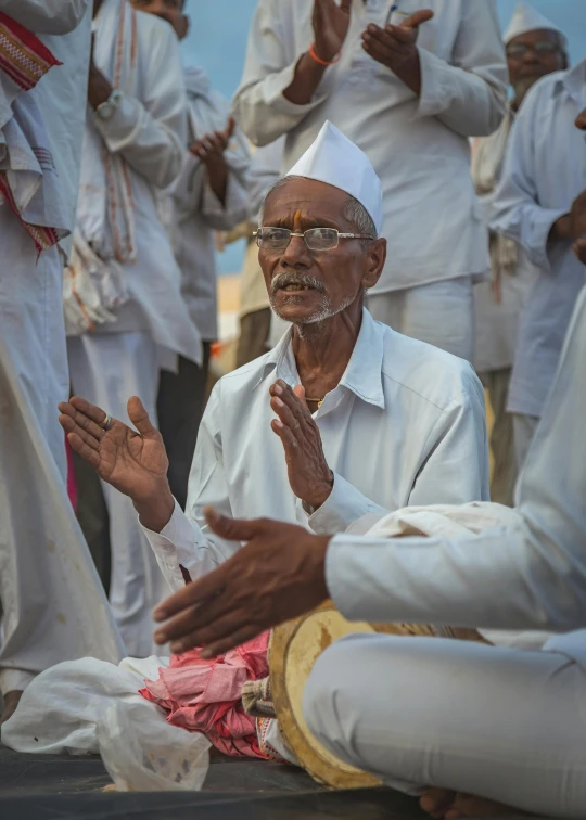 a man in white is sitting on a stool