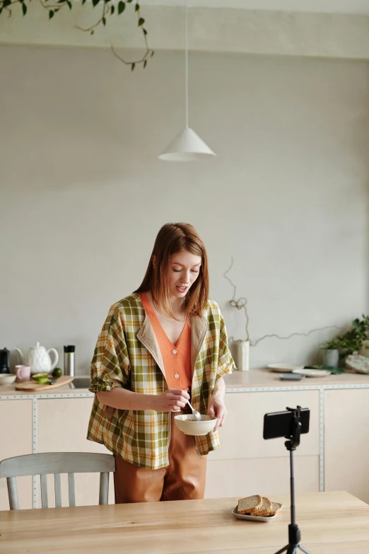 a woman holding a bowl stands behind a camera