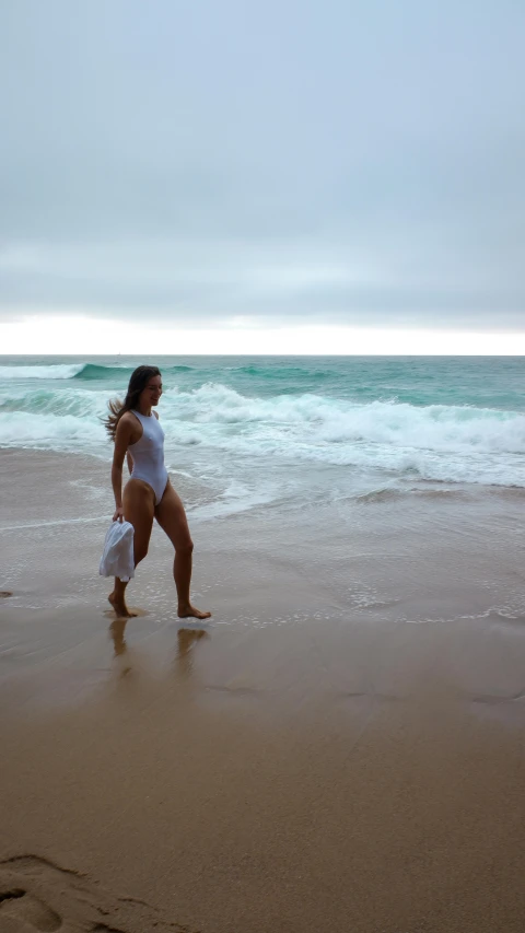 a woman standing on the beach near an ocean