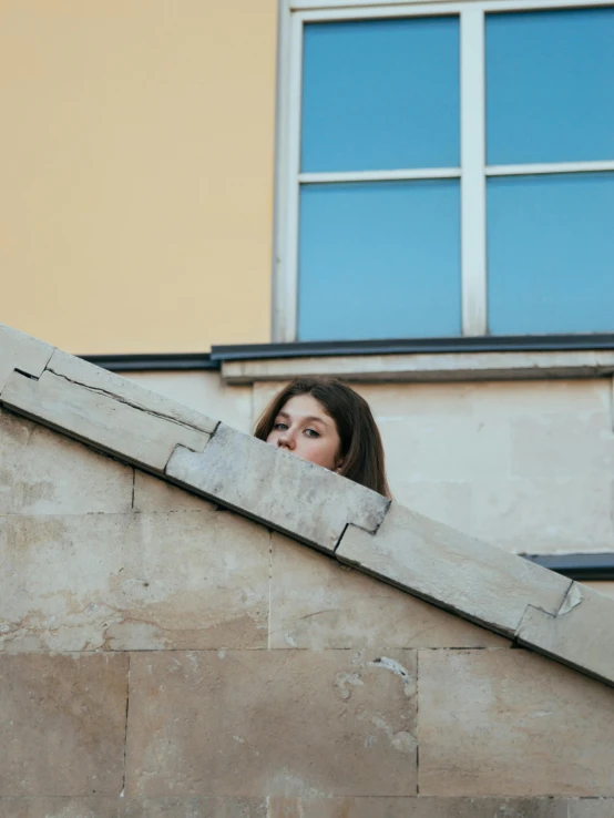 a woman is standing behind the edge of a concrete wall