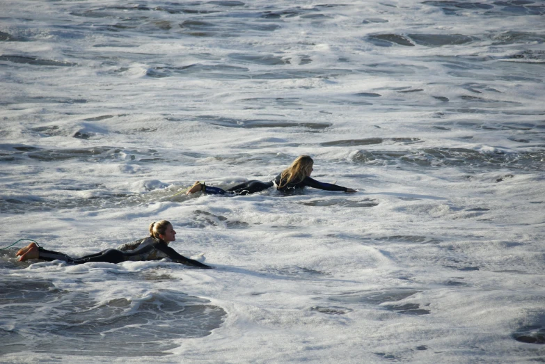 two surfers laying on their backs in the water