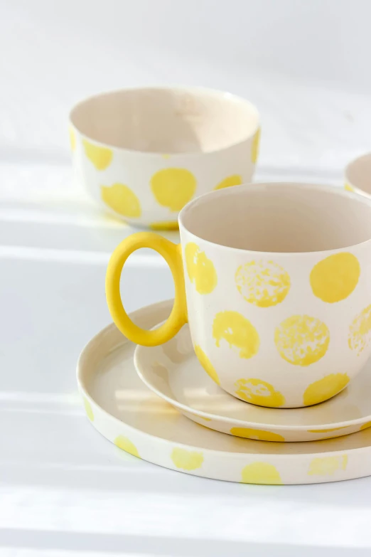 a set of yellow polka dot bowls and cups