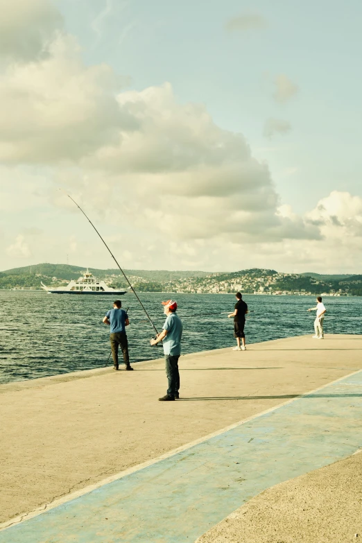 the men are fishing off the pier by the water