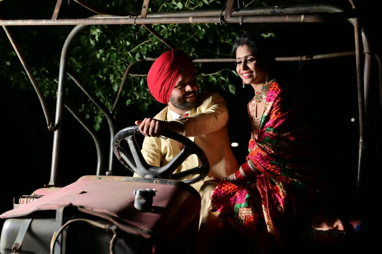 two people wearing indian attire sitting on a bed