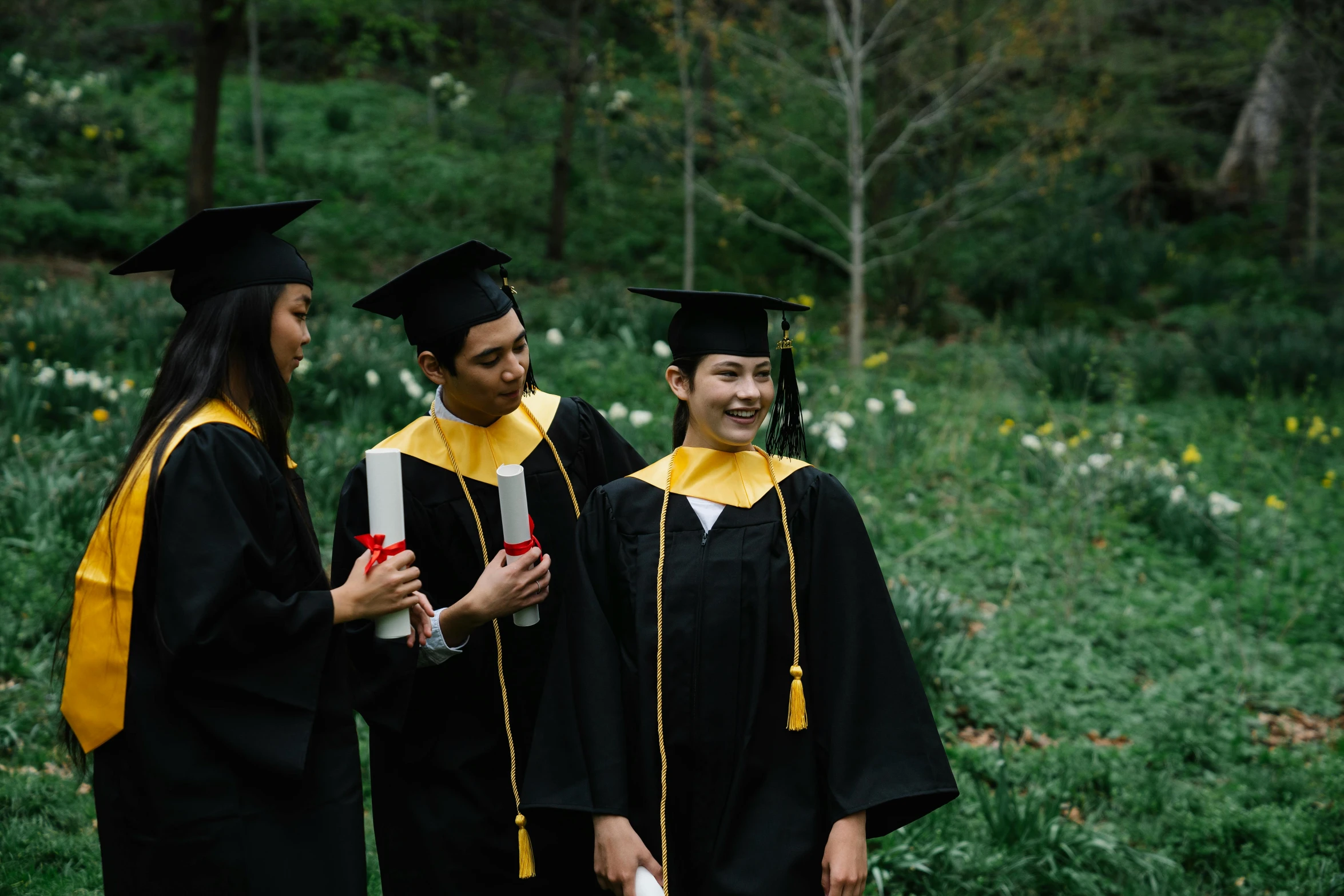 three people in graduation gowns standing together