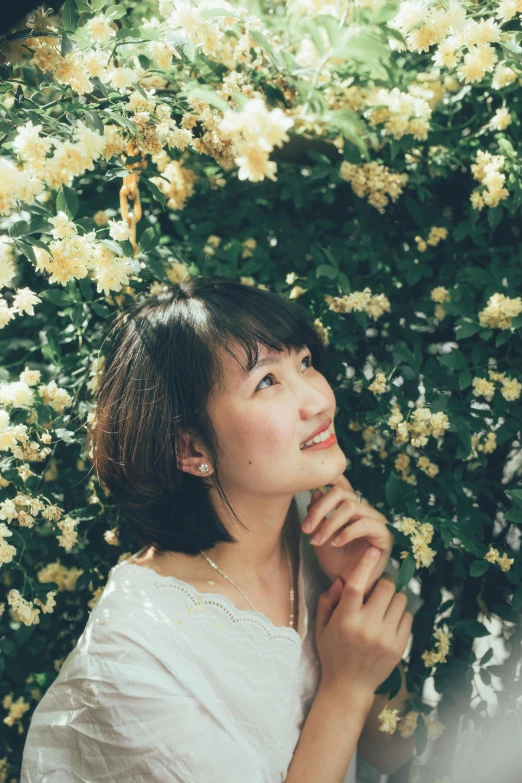 the woman is looking away while standing in front of flowers