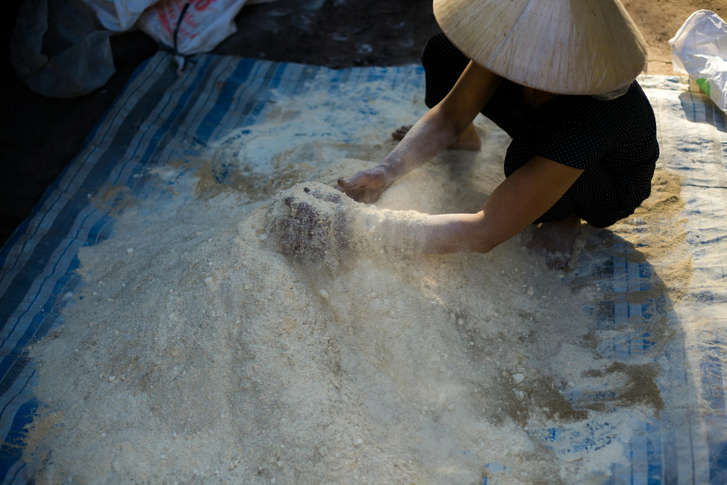 person in black shirt and straw hat working on flour