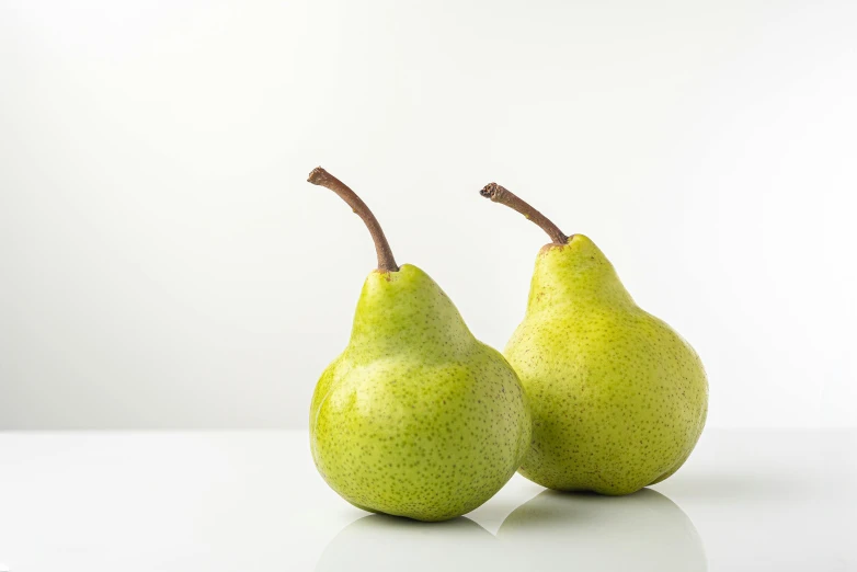 two pears sitting on top of a table next to each other