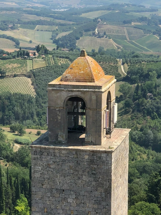 an old bell tower on top of a hill with rolling hills in the background