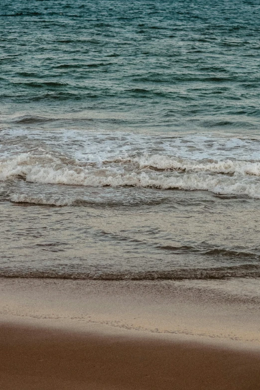 people are walking down the beach along the ocean