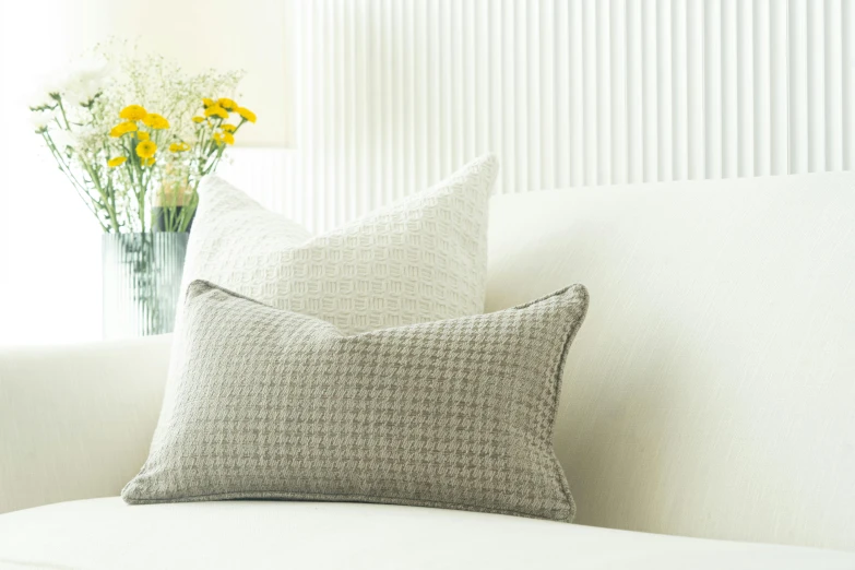 a white couch and a vase with yellow flowers