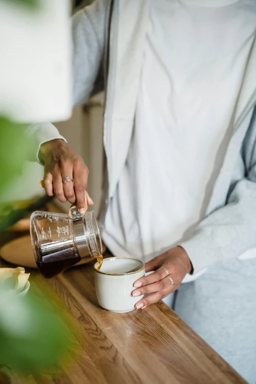 a person is pouring soing into a glass on a counter