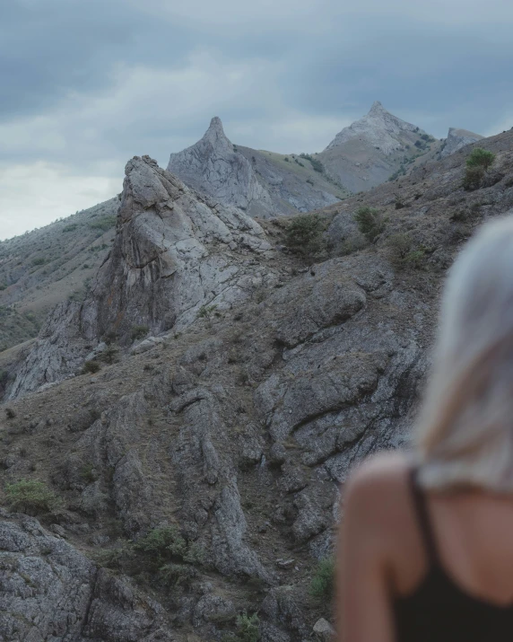 the woman is standing outside near the mountains