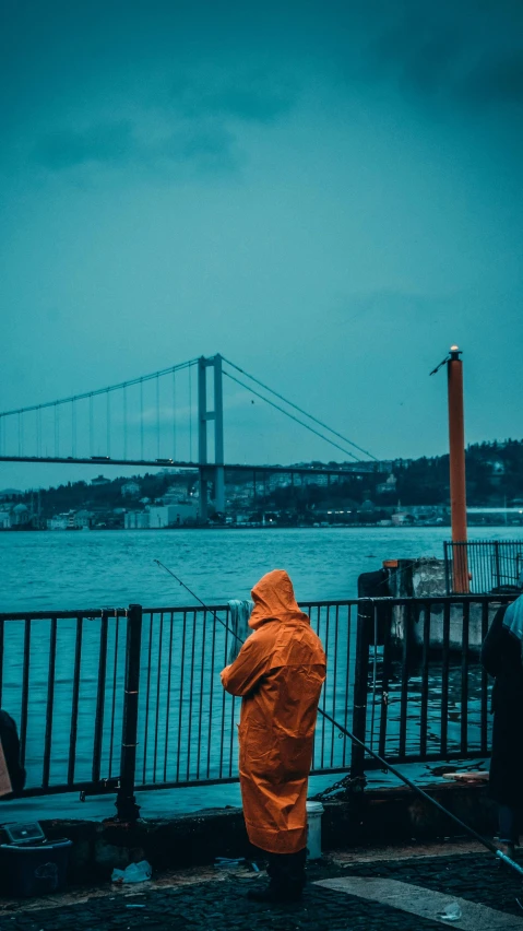 a person in yellow jacket standing on dock looking at the water