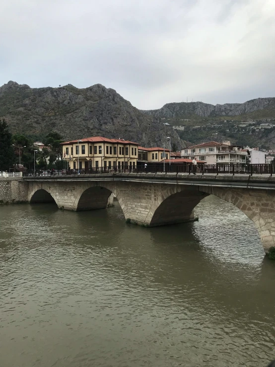 bridge over calm river in middle of town with mountain view