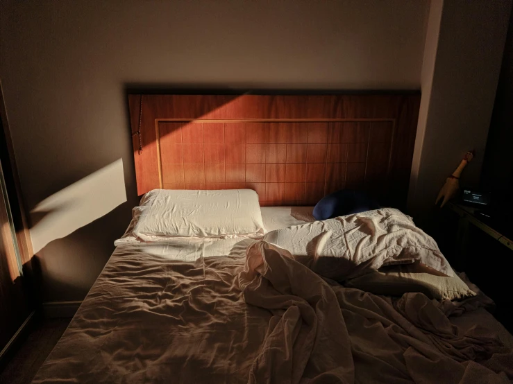 a single bed in a darkened room with sheets covering it