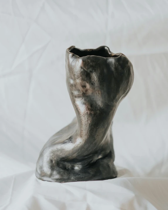 a silver vase sitting on top of a white sheet