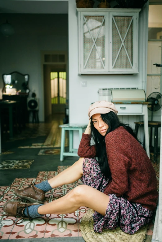 a young woman sitting on the floor, wearing boots