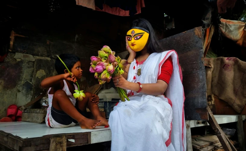 a woman sitting on a bench with another woman holding flowers