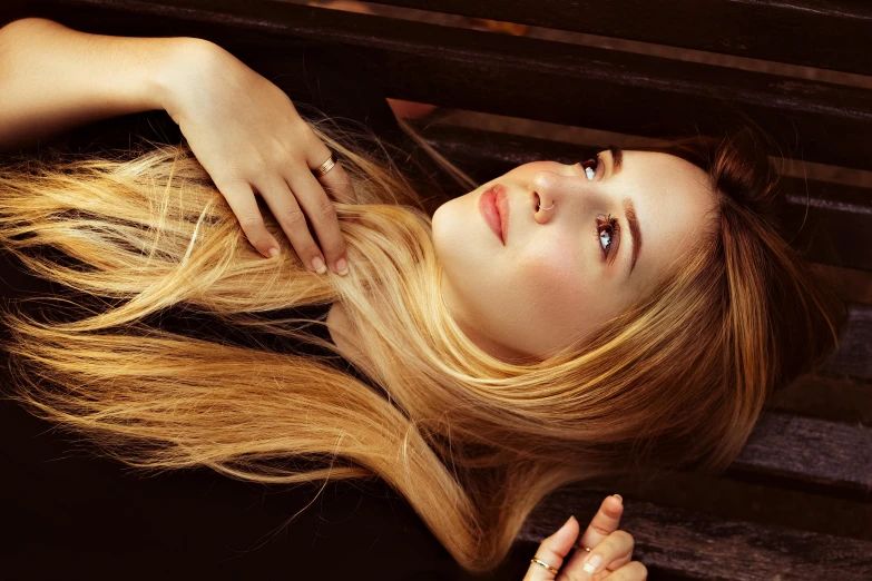 woman with long hair lying down on park bench