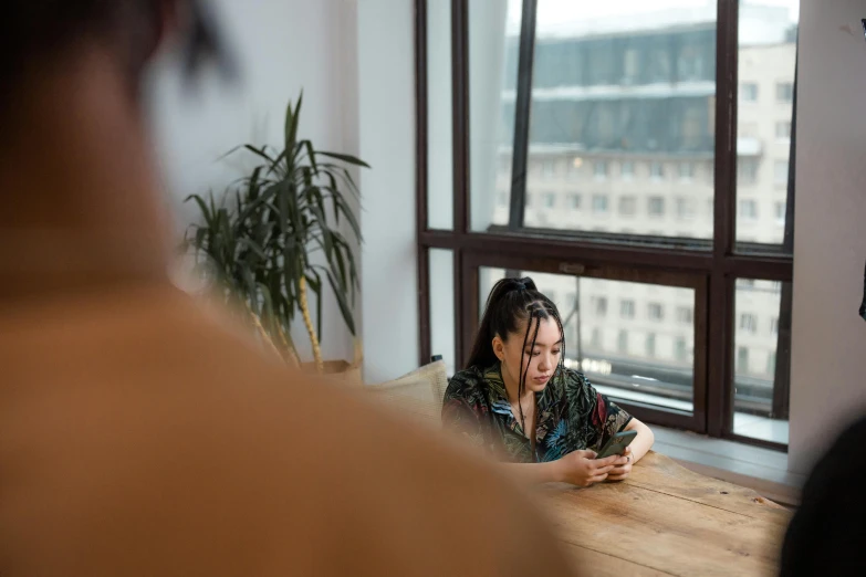 a woman is sitting at a table with her phone