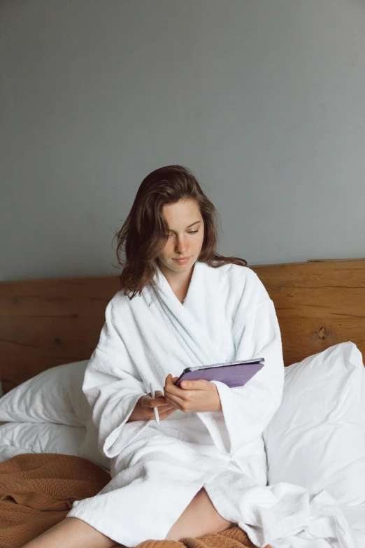 a woman is sitting on a bed while holding a clipboard