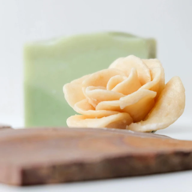 two pieces of soap and a flower sit on a wood block
