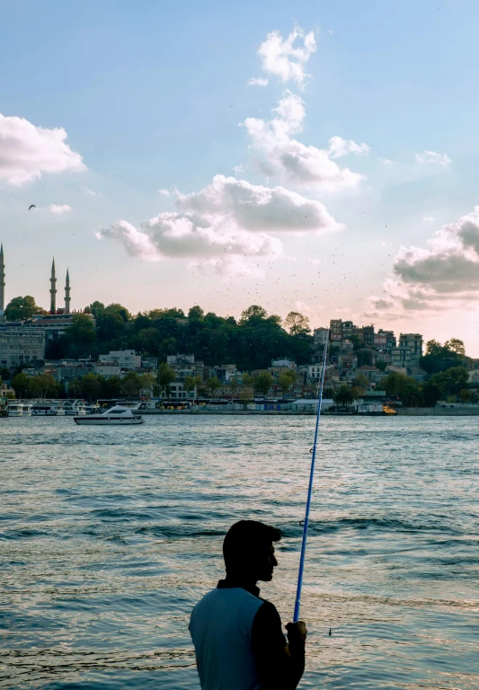 a man fishing on the water with a blue boat