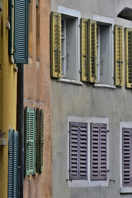 some windows and shutters against the wall of a building