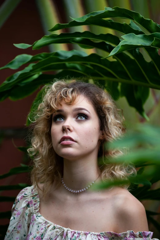 the woman is posing outside near a plant