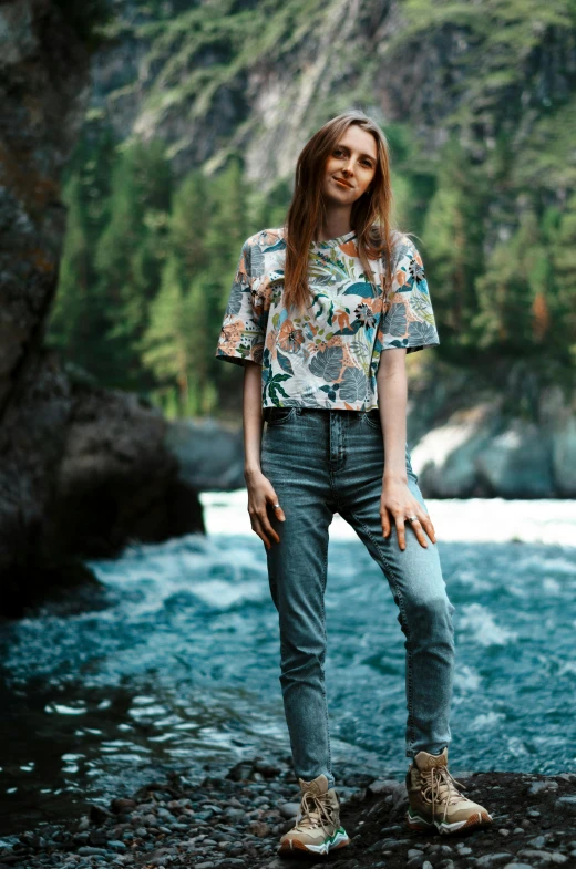 a young woman is posing on the shore of a river