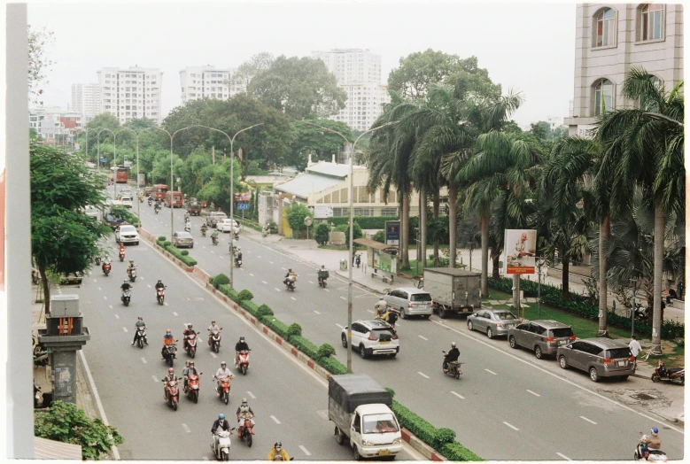 people and motorcyclists are riding down a very wide street