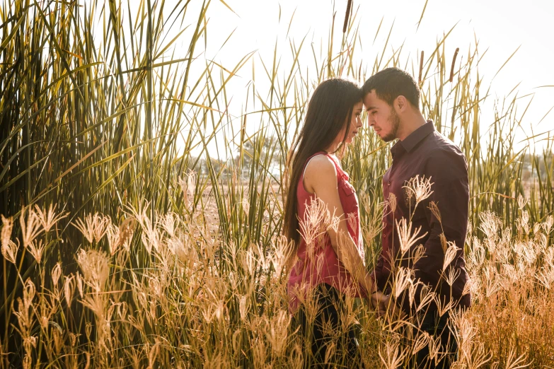 a young couple emcing by tall grass on an autumn day