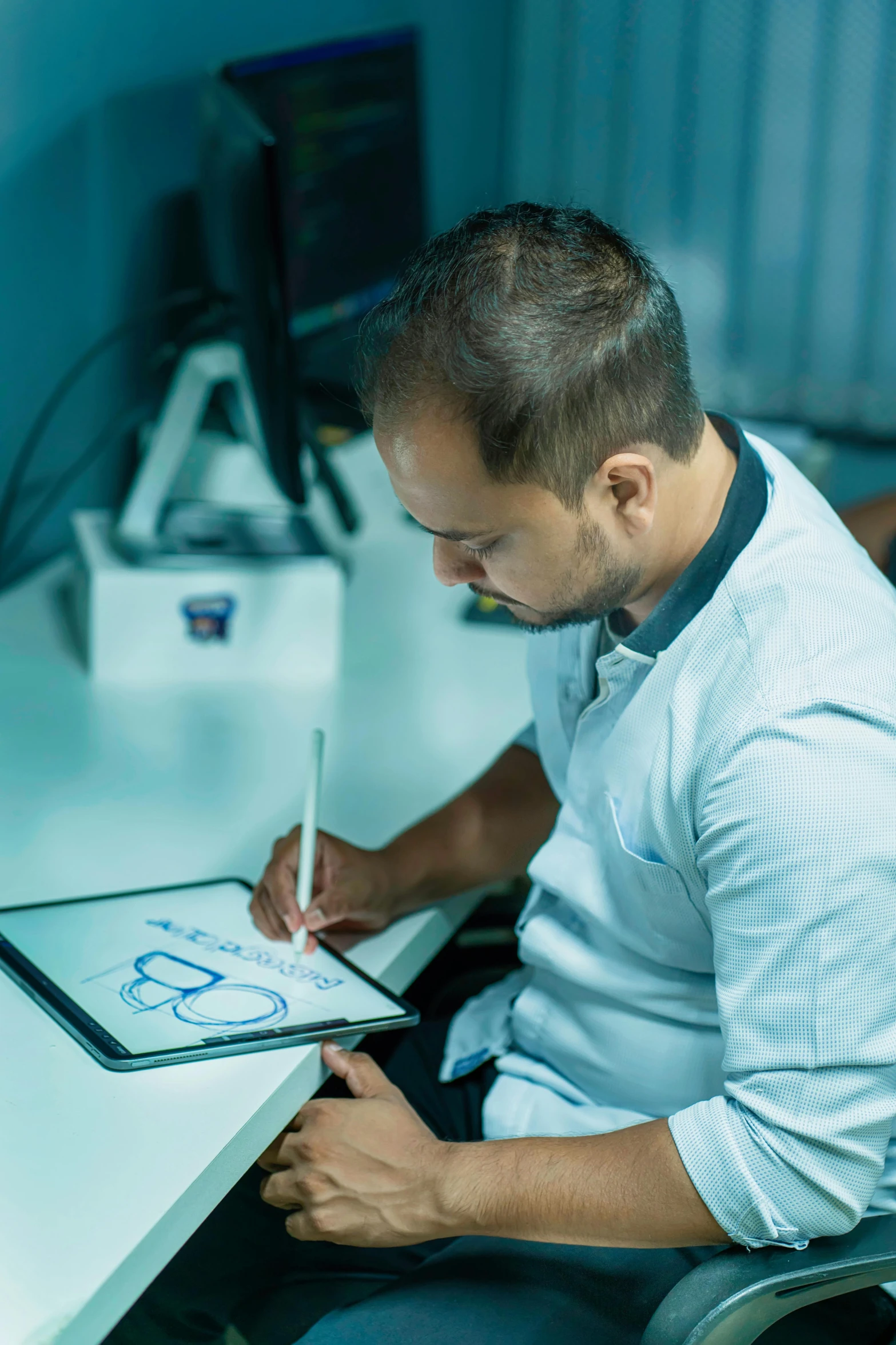 a man in a chair at a desk taking notes on his pad