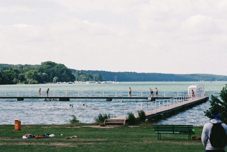 a group of people in bathing suits standing on a dock over a lake