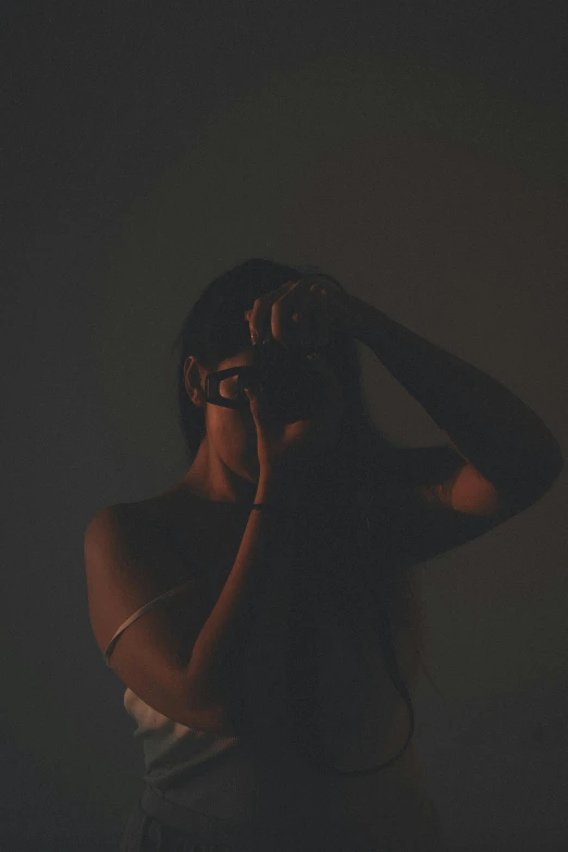 a woman wearing glasses poses with her head in her hands