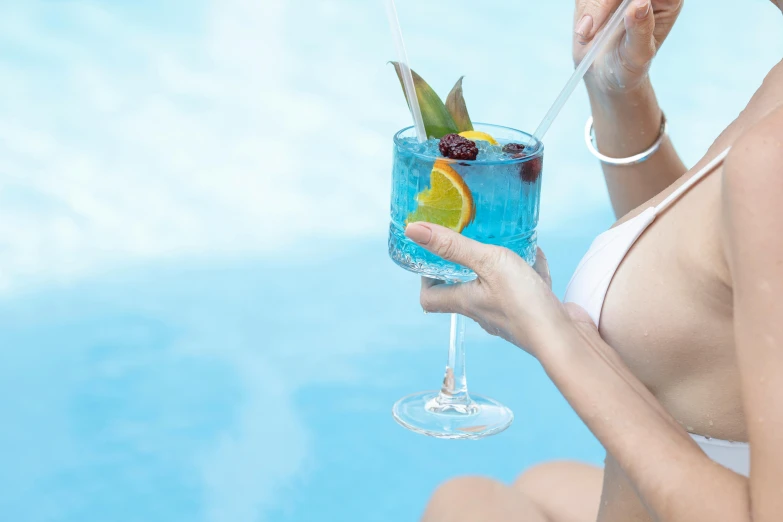 a woman wearing a white bikini is holding up a drink