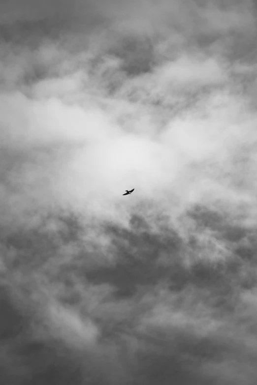 a plane flying in a cloudy sky on an overcast day