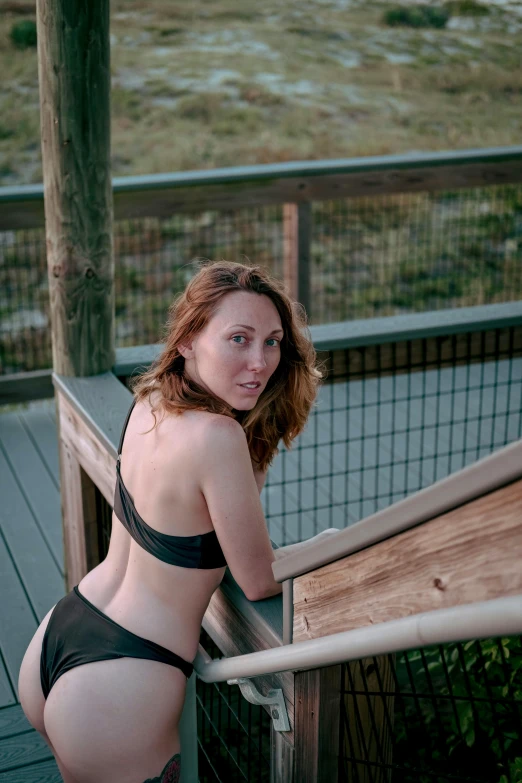 a beautiful woman in a thong top standing on top of a wooden deck