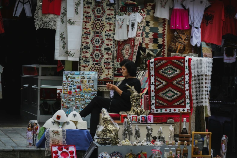 a person sitting on top of a chair in front of fabrics