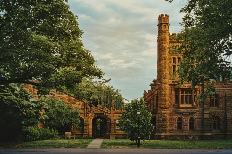 an old clock tower sits beside a tree lined road