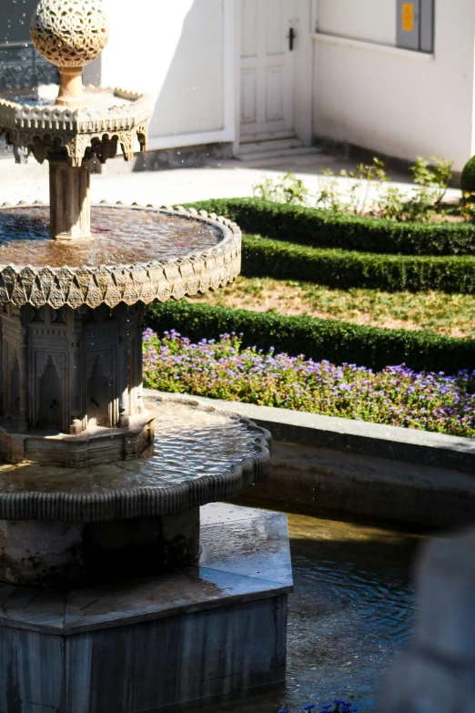 a water fountain surrounded by flowers and a house