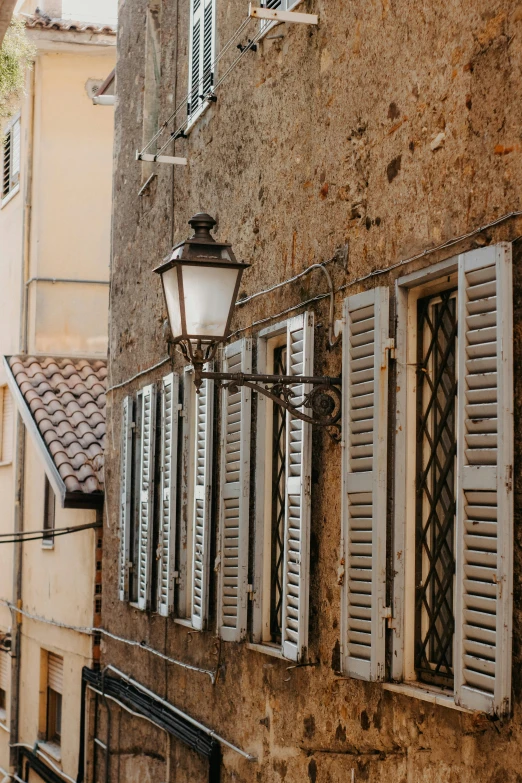 an old building with shutters and a lamp